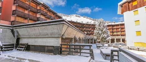 Un patio cubierto de nieve con una escalera de madera que lleva a un edificio con balcones.