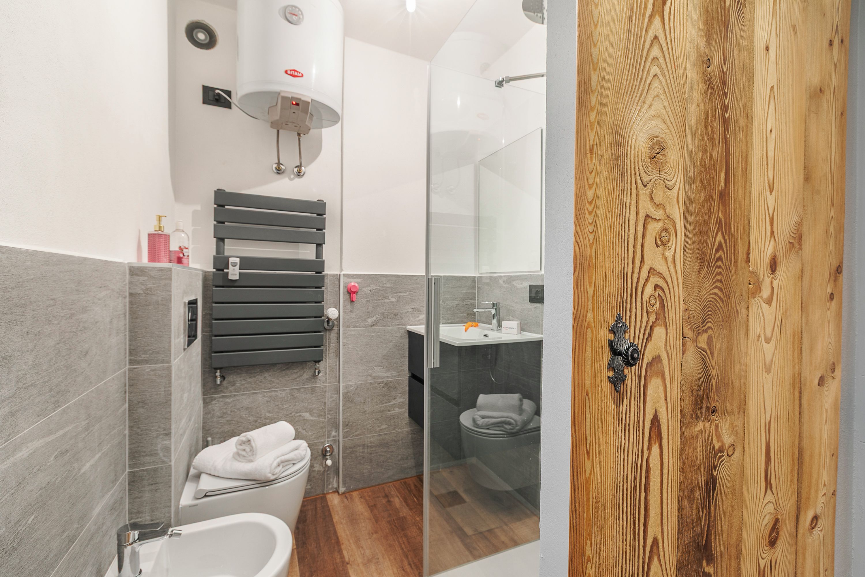 Un baño moderno con bañera, ducha y retrete. Hay un perchero y un espejo.