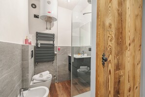 Un baño moderno con bañera, ducha y retrete. Hay un perchero y un espejo.