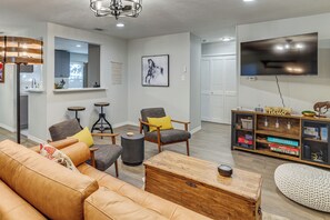 Una sala de estar moderna con un sofá de cuero, una mesa de centro de madera y un televisor en la pared.