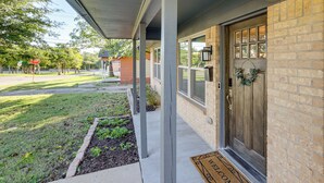 A residential house with a front porch, a brick exterior, and a wooden door. - Dog-friendly Dallas Home w/ Fenced Yard! (Dallas)