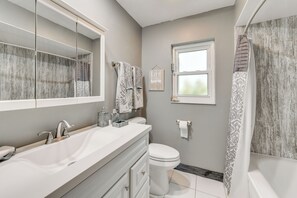 A modern bathroom with a large mirror, a white sink with marble fixtures, a toilet, and a shower with a patterned curtain. - Private Hot Tub, Pool & Yard: Modern Bradenton Gem (Bradenton)