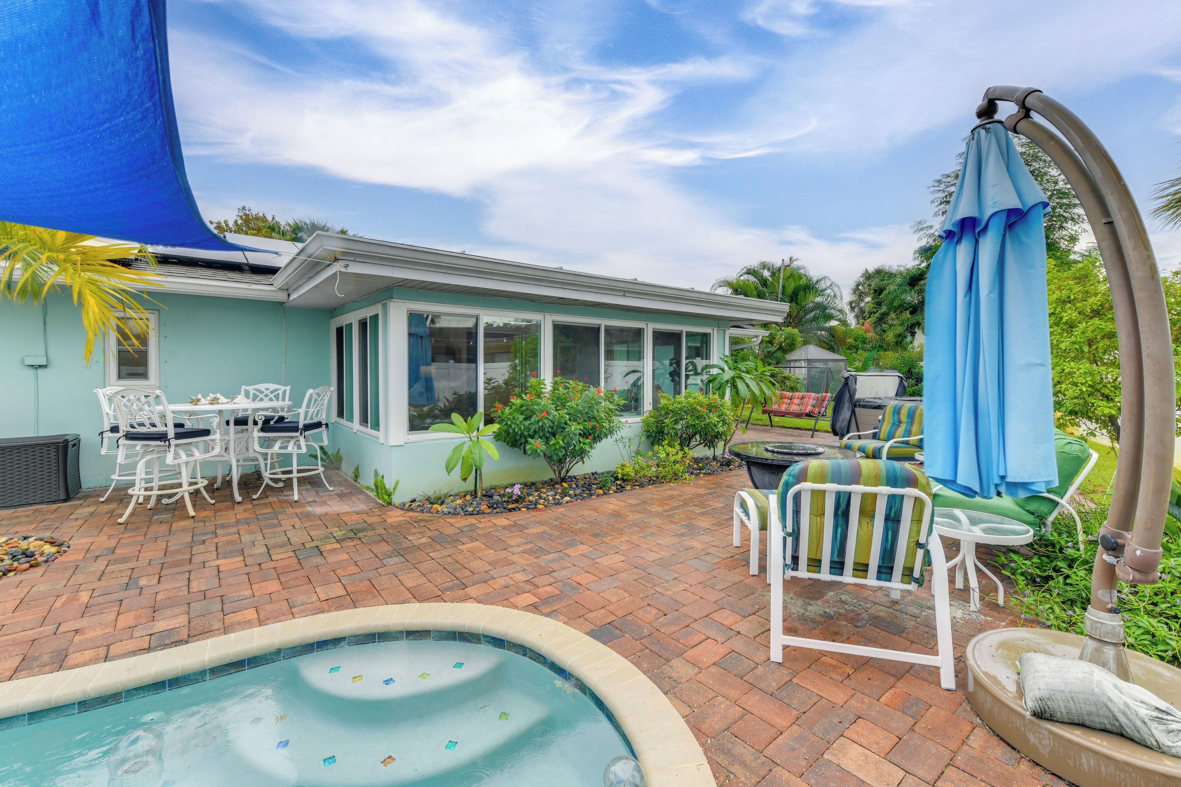 A backyard with a swimming pool, patio furniture, and a covered seating area.