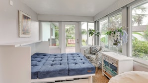 A bedroom with a bed, a dresser, a chair, and a window with a view of greenery. - Private Hot Tub, Pool & Yard: Modern Bradenton Gem (Bradenton)