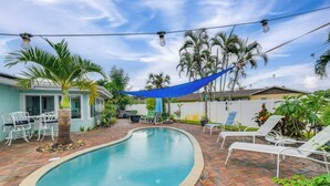A swimming pool with lounge chairs, a palm tree, and a blue shade sail. - Private Hot Tub, Pool & Yard: Modern Bradenton Gem (Bradenton)