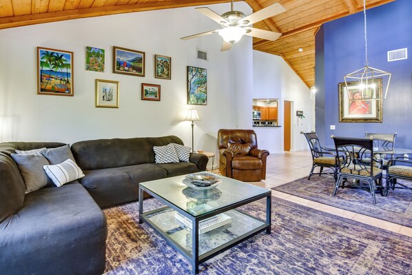 A living room with a glass coffee table, leather sofa, and a dining area with chairs. - 5 Mi to Anna Maria Island: Apt w/ Pool Access! (Bradenton)