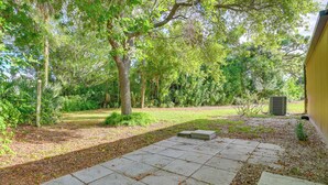 A paved patio area with stone tiles, surrounded by lush greenery and trees. - 5 Mi to Anna Maria Island: Apt w/ Pool Access! (Bradenton)