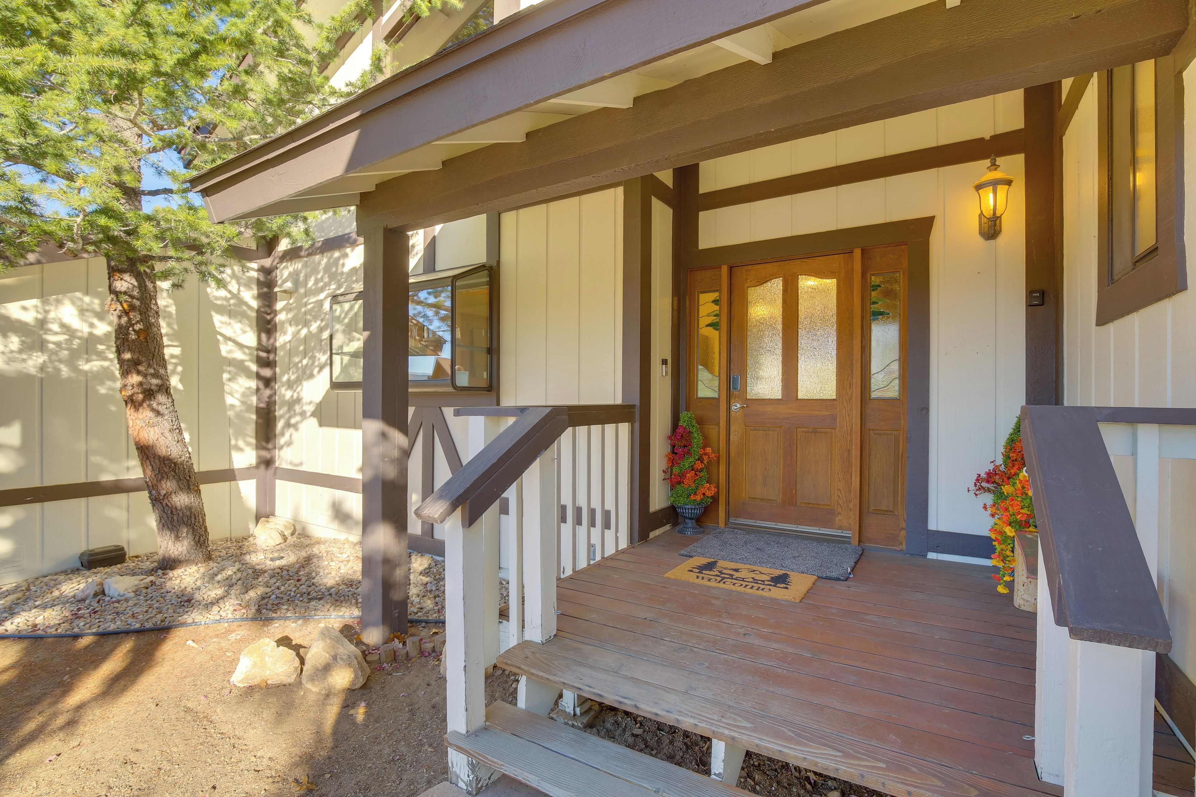A wooden porch with a bench, a door, and a welcome mat.