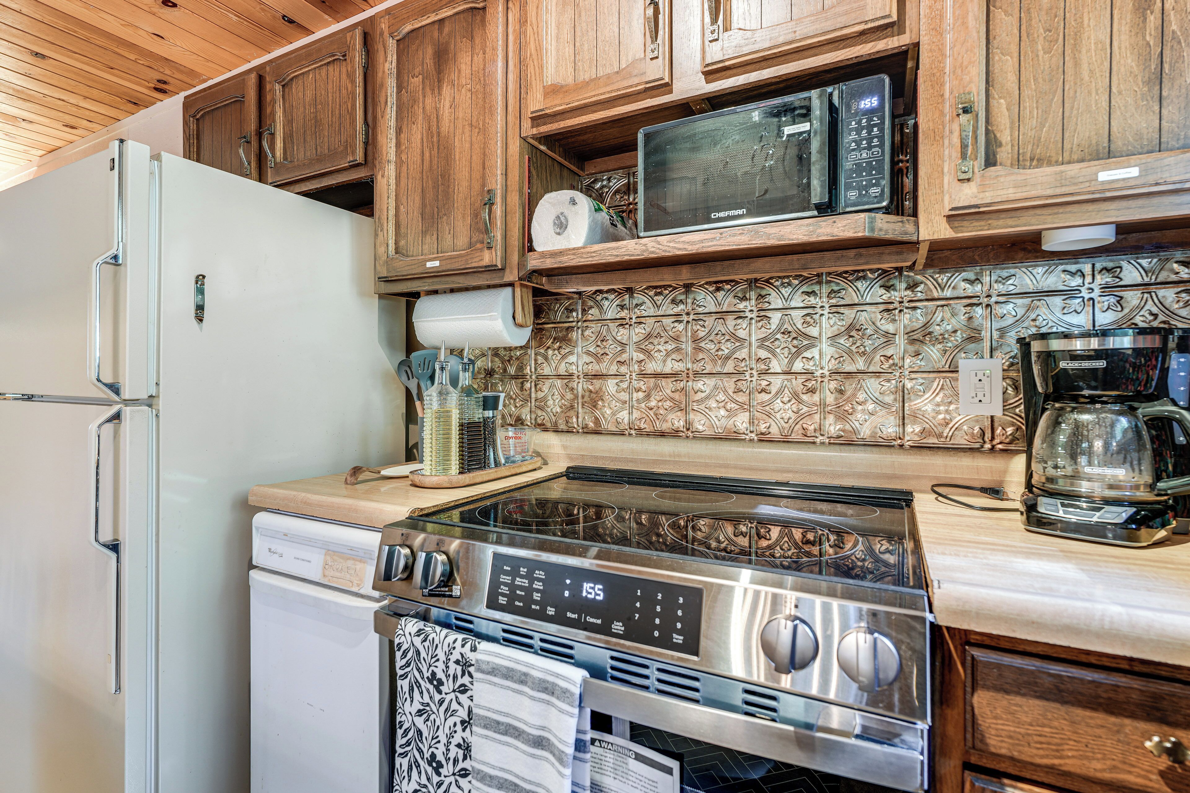 A kitchen with wooden cabinets, a stainless steel stove, a microwave, and a refrigerator.