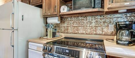 A kitchen with wooden cabinets, a stainless steel stove, a microwave, and a refrigerator.
