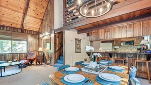 A wooden interior with a dining area set for four, a kitchen with a microwave, and a staircase leading to an upper level. - 4 Mi to State Park: Quiet Escape w/ Deck in Arnold (Arnold)