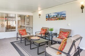 A modern living room with a glass door leading to a patio, a cityscape painting on the wall, and a dining table with a plate. - Suburban Home 9 Mi to Dtwn Denver: Outdoor Oasis! (Aurora)