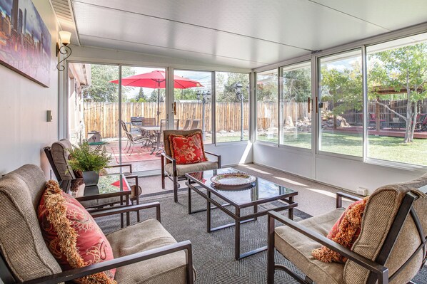 A sunroom with a glass door leading to a backyard patio area. - Suburban Home 9 Mi to Dtwn Denver: Outdoor Oasis! (Aurora)