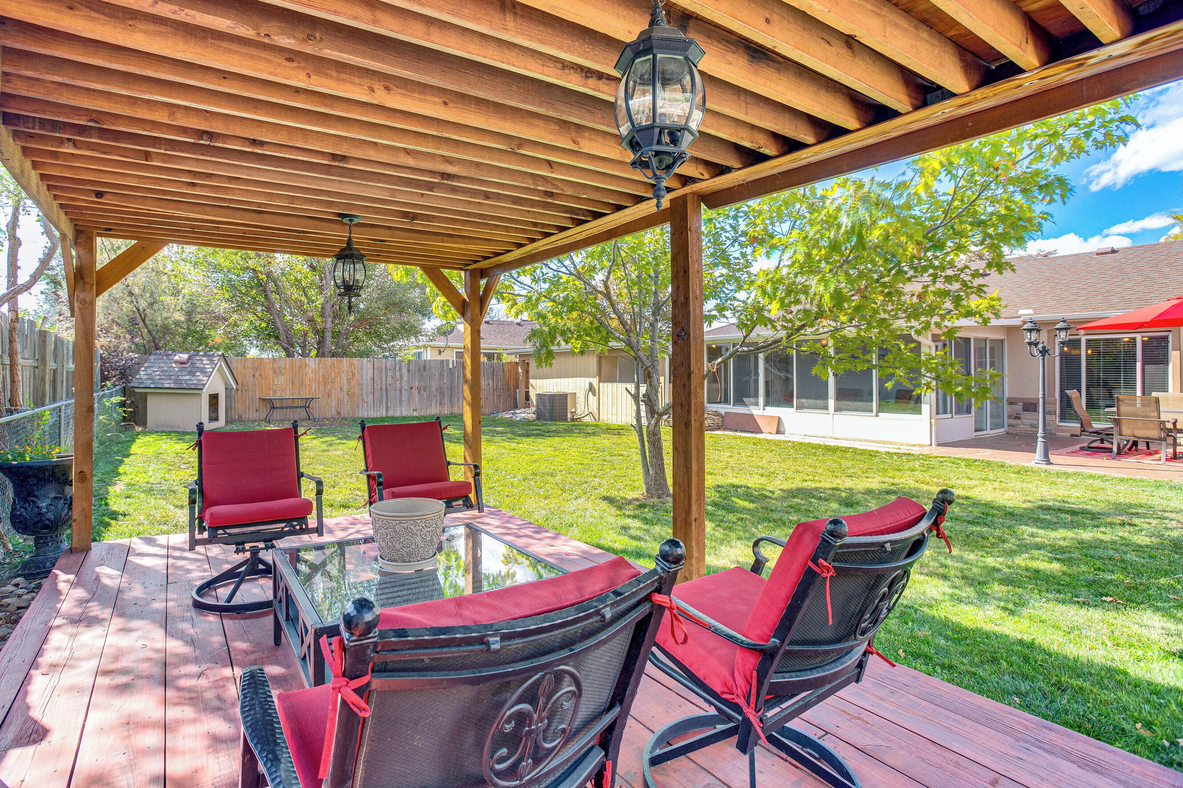 A covered patio with a glass table, red chairs, and a hanging lantern.