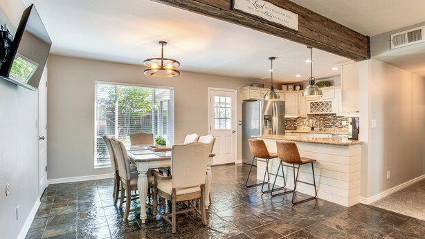 A spacious kitchen with a dining area, featuring a stone tile floor, wooden ceiling beams, and pendant lighting. - Suburban Home 9 Mi to Dtwn Denver: Outdoor Oasis! (Aurora)