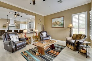 A spacious living room with leather sofas, a coffee table, and a large window with blinds. - Mtn-view Patio Oasis! Luxe Family Home in Peoria (Peoria)