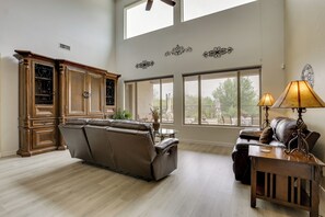 Ein geräumiges Wohnzimmer mit einer Ledersofa, einer Holzkommode und einem Essbereich mit Tisch und Stühlen.