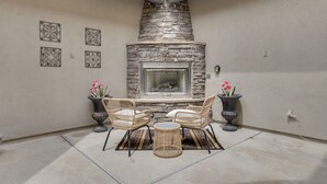 A patio with a stone fireplace, wicker furniture, and potted plants. - Mtn-view Patio Oasis! Luxe Family Home in Peoria (Peoria)