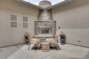 A patio with a stone fireplace, wicker furniture, and potted plants. - Mtn-view Patio Oasis! Luxe Family Home in Peoria (Peoria)