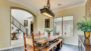 A dining area with a long wooden table, chairs with woven backs, and a chandelier. - Mtn-view Patio Oasis! Luxe Family Home in Peoria (Peoria)