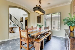 A dining area with a long wooden table, chairs with woven backs, and a chandelier. - Mtn-view Patio Oasis! Luxe Family Home in Peoria (Peoria)