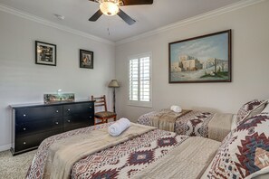 Un dormitorio con dos camas, un tocador, una silla, un cuadro y una ventana.