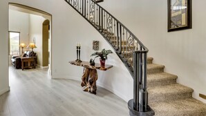 Una scala con ringhiera in legno e inferriata che conduce a un piano superiore rivestito di moquette.