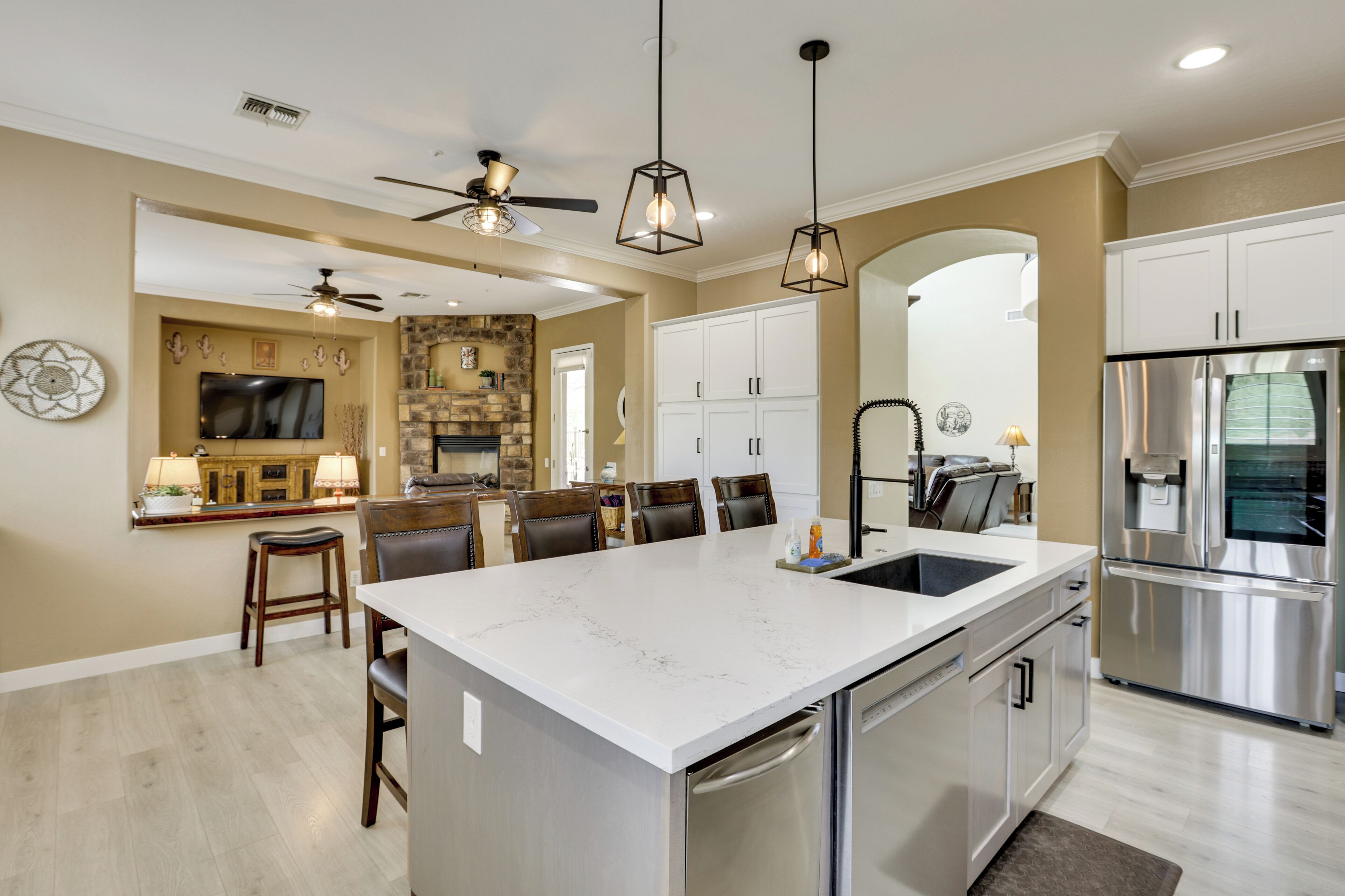 A modern kitchen with a central island, stainless steel appliances, and a dining area with a stone accent wall.