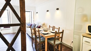 Zona pranzo con un tavolo in legno apparecchiato per quattro persone, circondato da sedie di legno con sedili imbottiti.