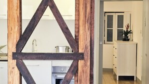 Una struttura in legno rustica con un motivo a croce, che conduce a una cucina moderna e a un corridoio con un armadietto bianco e una pianta.