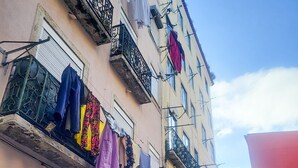 Un vicolo stretto fiancheggiato da edifici e balconi con panni stesi, sotto un cielo sereno.
