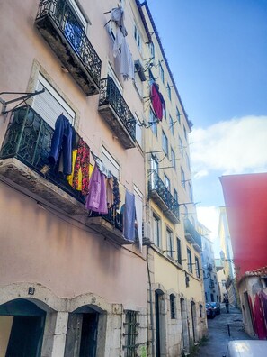 A narrow street with buildings, balconies with clothes hanging, and a clear sky. - Lisbon Alfama Charming Apartment (Lisboa ciudad)