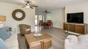 A spacious living room with a wooden coffee table, a sofa, a TV, and a dining area with chairs and a table. - Fish, Swim & Boat: Riverfront Port Charlotte Home (Port Charlotte)