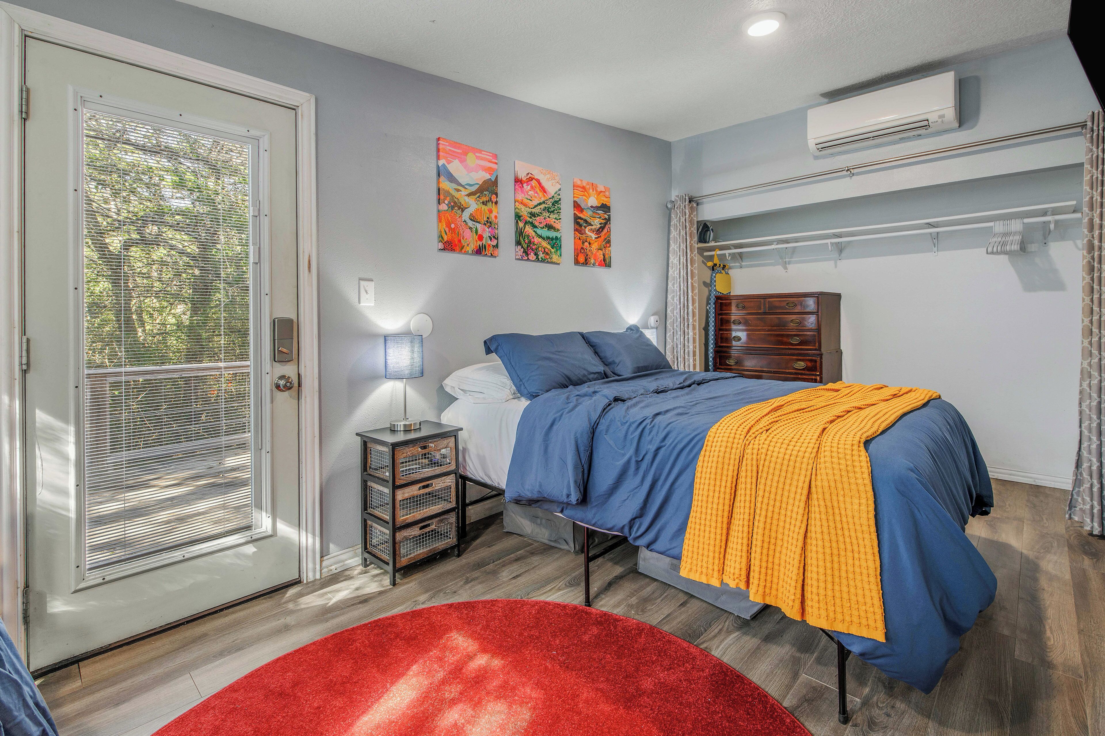 A bedroom with a bed, a nightstand, a dresser, and a red rug.