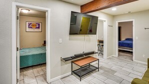 A compact room with a bed, a desk, a TV mounted on the wall, and a door leading to another room. - Explore LA & Long Beach: Compton Condo w/ Patio (Compton)