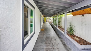 A covered corridor with a tiled floor, a white wall, and a wooden beam ceiling. - Explore LA & Long Beach: Compton Condo w/ Patio (Compton)