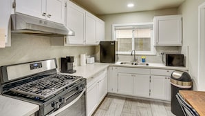 A modern kitchen with white cabinets, a stainless steel range hood, a built-in microwave, and a sink. - Explore LA & Long Beach: Compton Condo w/ Patio (Compton)