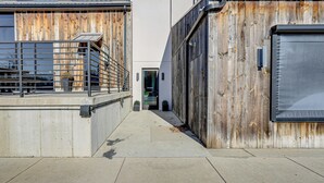 A narrow concrete pathway flanked by wooden fences and metal gates, leading to a building entrance. - Between Restaurant & Brewery! Chic Perrysburg Apt (Perrysburg)