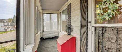 A narrow corridor with a red bench, a fan, and a decorative wreath on a window.