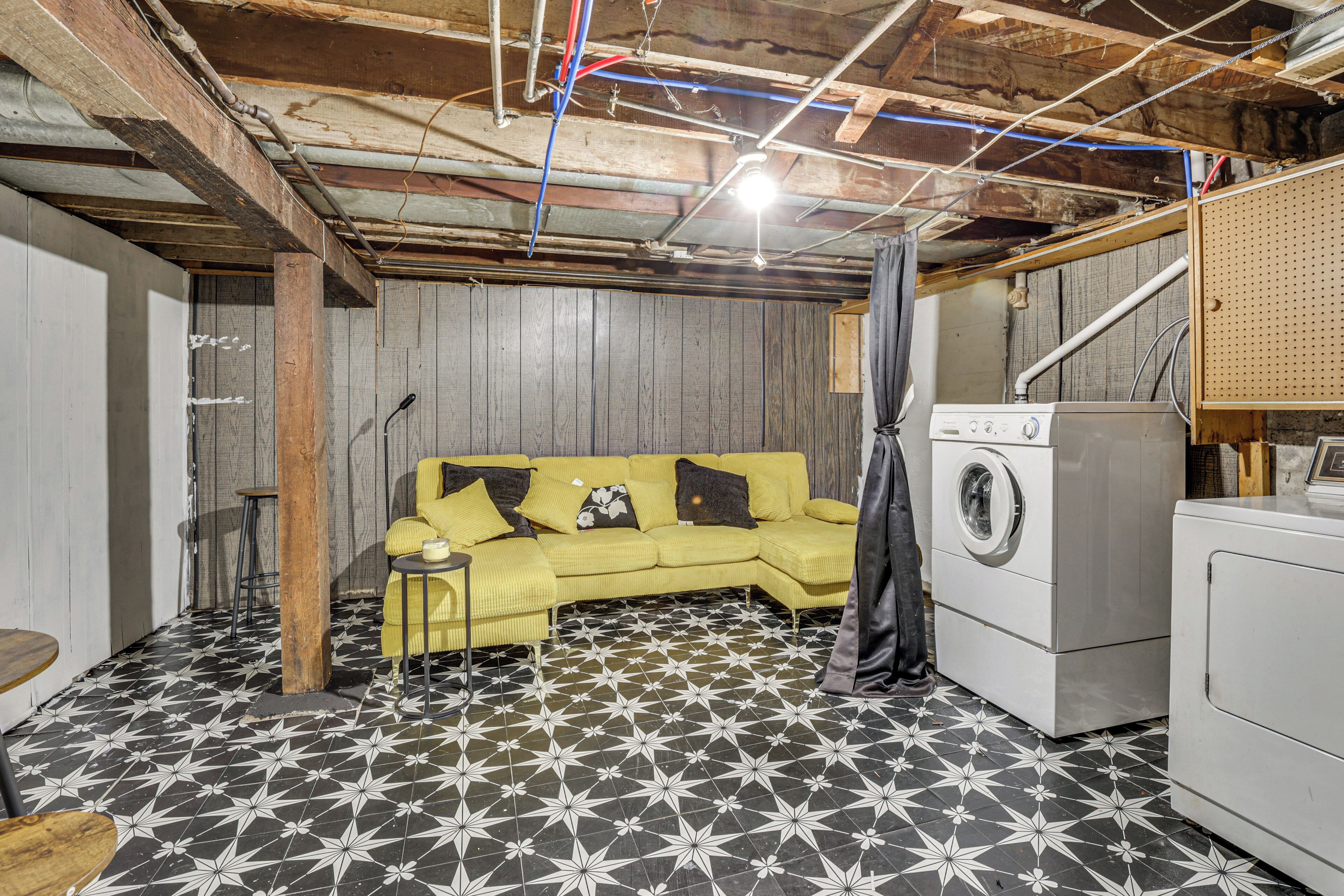A laundry room with a yellow couch, washing machine, and a patterned floor.