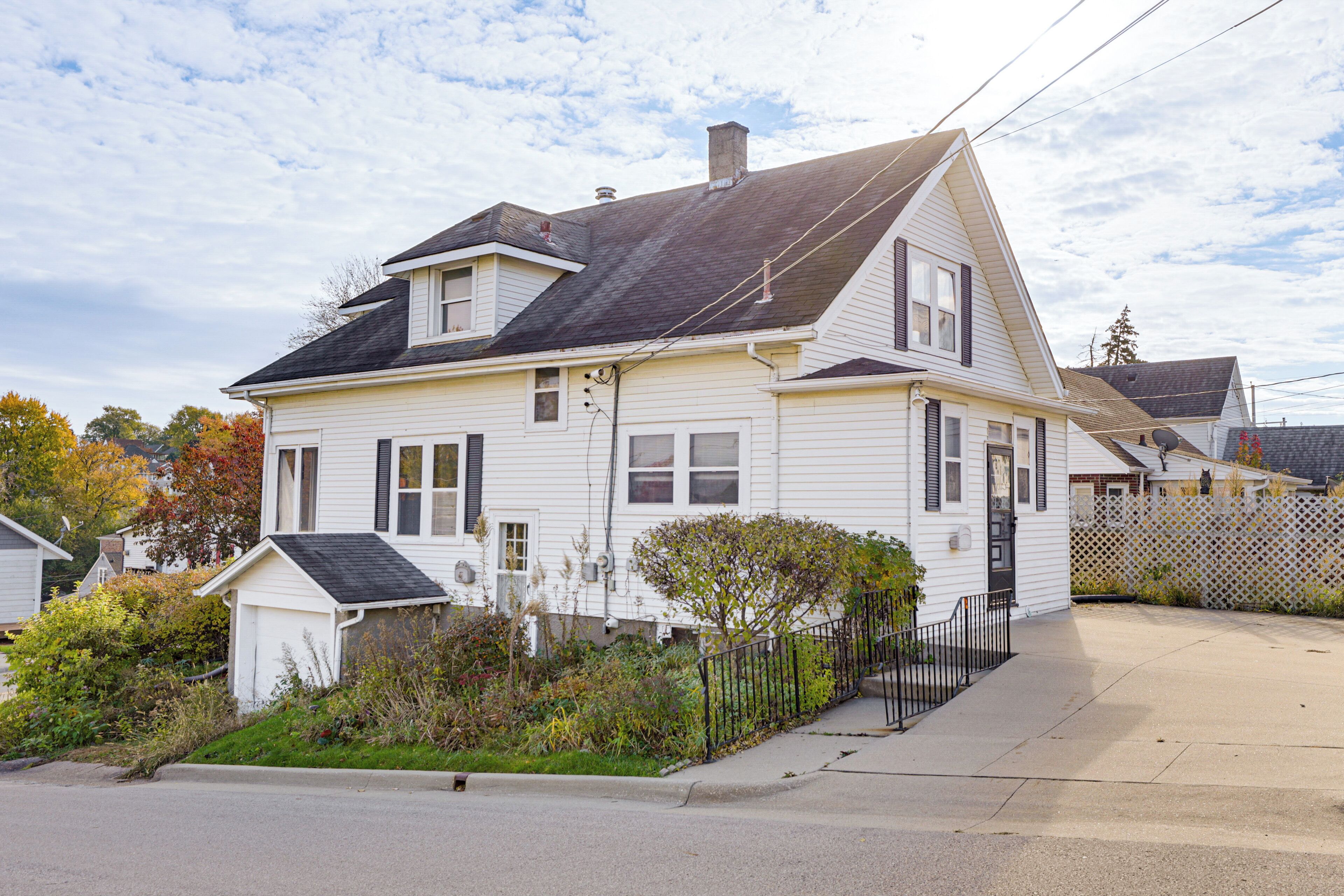 A two-story house with a gabled roof, a front porch, and a small attached garage.