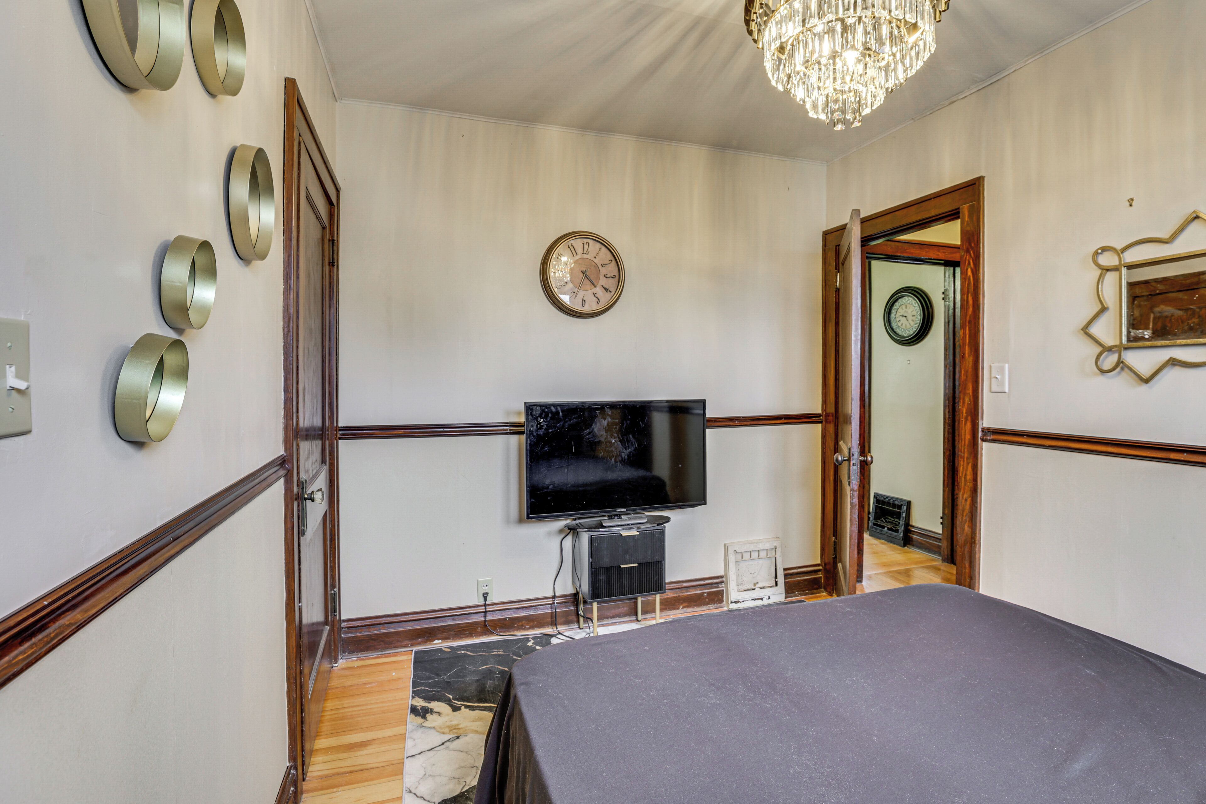 Une chambre à coucher avec un lit, une télévision, une horloge et un miroir.