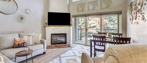 A living room with a fireplace, a sofa, a coffee table, and a TV mounted on the wall.