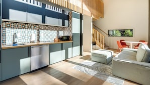 Una cocina moderna con un salpicadero de diseño, lavavajillas integrado y una zona de comedor con sofá y sillas rojas.