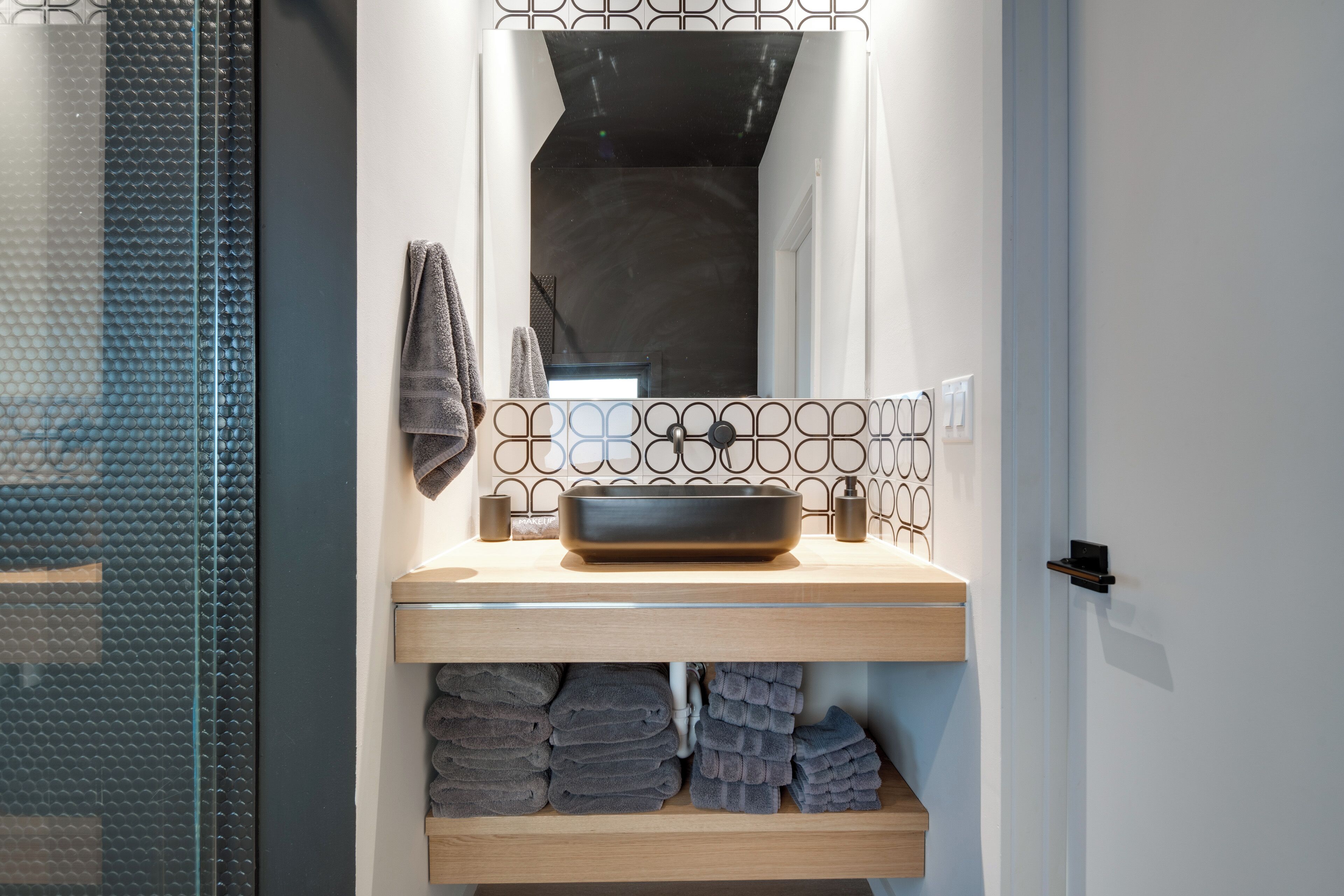 Une salle de bain avec un lavabo moderne, un miroir et un porte-serviettes.