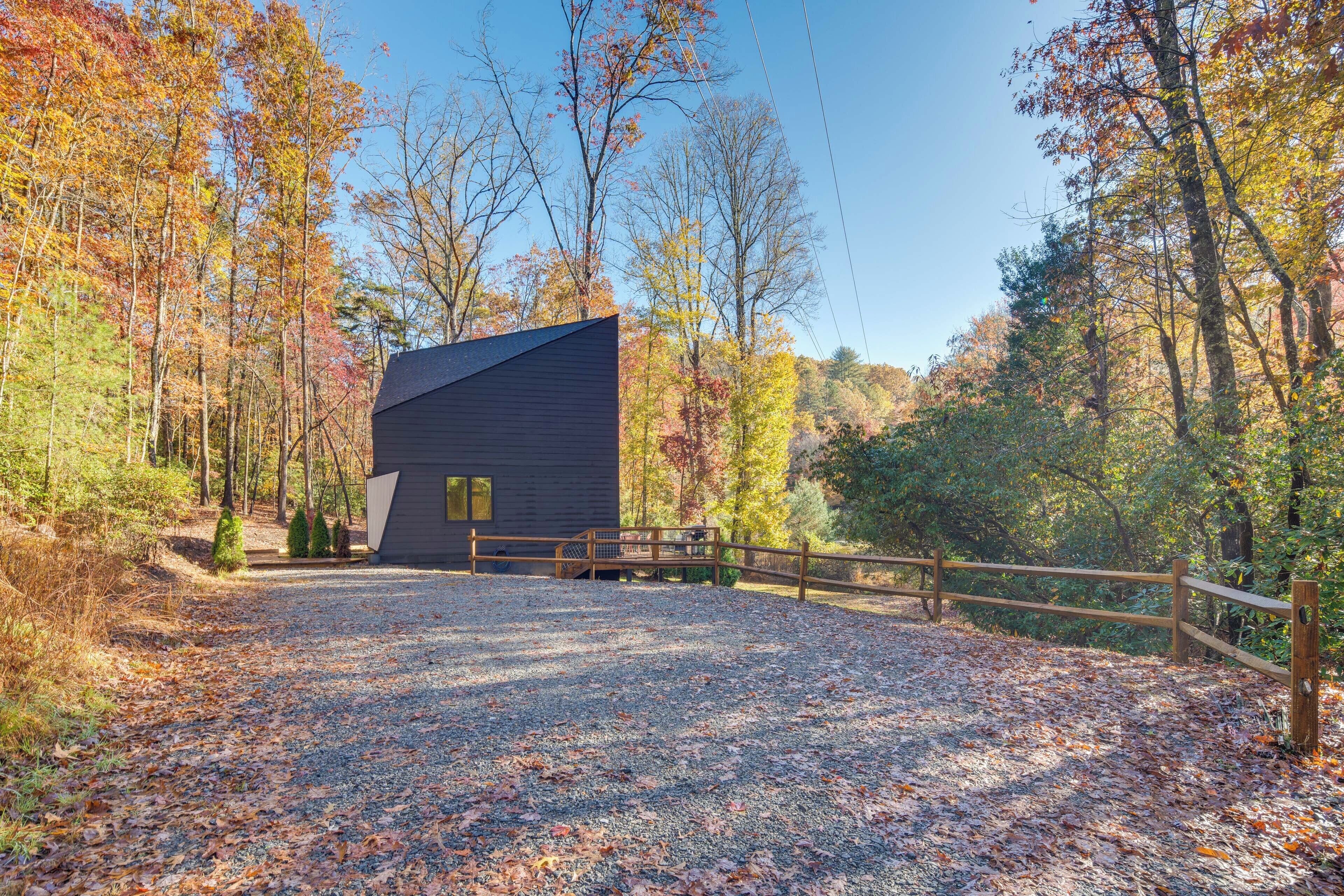 A modern building with a sloped roof, surrounded by a gravel driveway and a wooden fence.