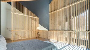 Un dormitorio con cama, lámpara trípode y listones de madera en las paredes.
