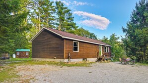 A wooden cabin with a gravel driveway, a small porch, and a wooden deck. - 9 Mi to Hickory Ski Center: Wooded Warrensburg Gem (Warrensburg)