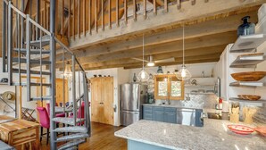 Una cocina amplia con una isla central, vigas de madera y electrodomésticos modernos.
