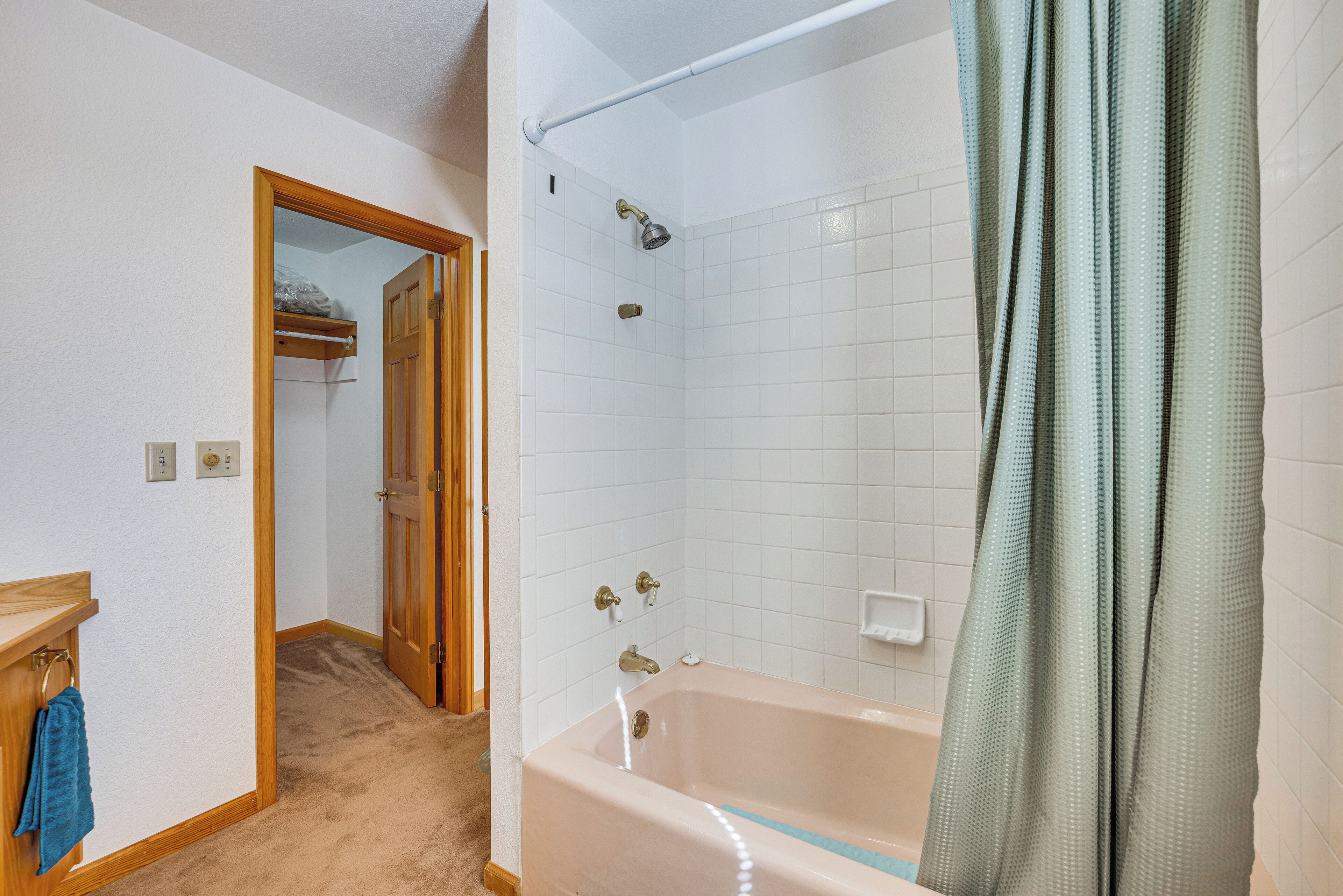 A bathroom with a bathtub, shower, and a wooden door leading to another room.